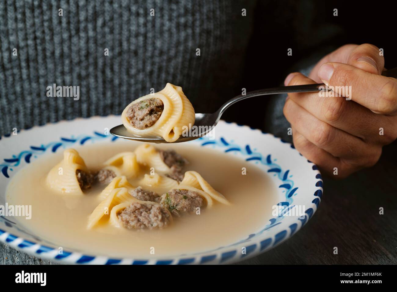 Die Nahaufnahme eines Mannes, der kurz davor steht, etwas Escudella de Nadal zu essen, auch bekannt als sopa de Galets, eine Suppe mit Galets Pasta, die typischerweise zu Weihnachten in Katalon gegessen wird Stockfoto