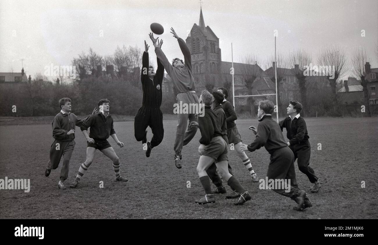 1950er, historisch, Spieler des englischen Rugby-Union-Teams der Schulen, England, Großbritannien, auf einem Rugby-Feld, üben eine Reihe mit zwei Spielern in Trainingsanzügen, die auf den Ball springen, während andere darauf warten, ihn zu fangen, wenn er herunterkommt. Stockfoto