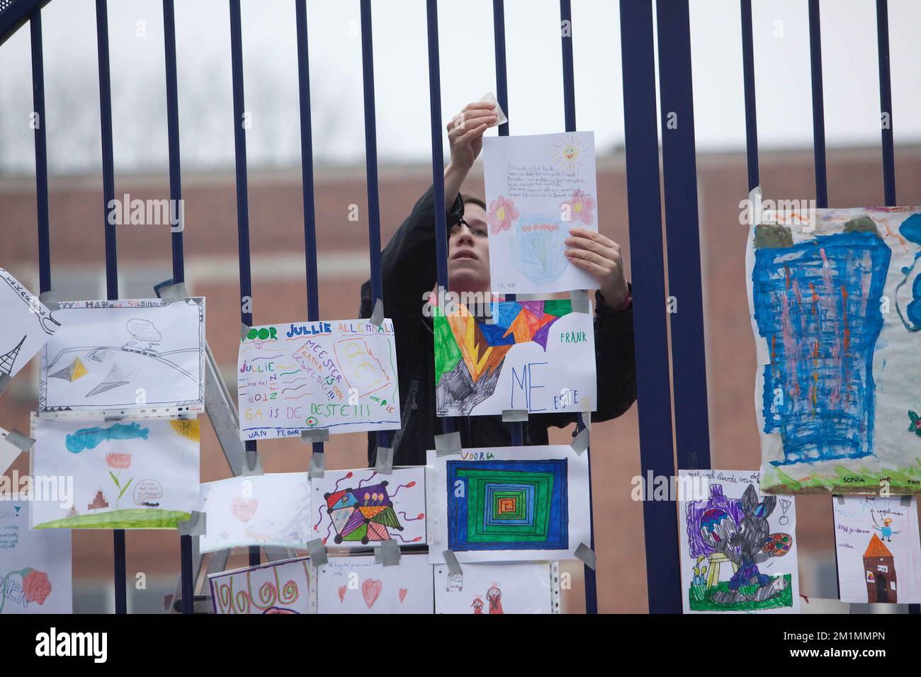 20120316 - HEVERLEE, BELGIEN: Abbildung zeigt eine Frau, die eine Zeichnung am Tor der Grundschule (Basisschool - ecole Primaire) Sint-Lambertusschool, in Heverlee, Freitag, den 16. März 2012. Bei einem schrecklichen Busunfall am Dienstagabend in einem Tunnel, in Sierre, Valais, Schweiz, 28 Menschen, Darunter 22 Kinder, starben, 24 andere wurden verletzt. Die Kinder aus zwei Schulen von Lommel und Heverlee waren nach dem Skiurlaub auf dem Heimweg. BELGA FOTO CHRISTOPHE LEGASSE Stockfoto