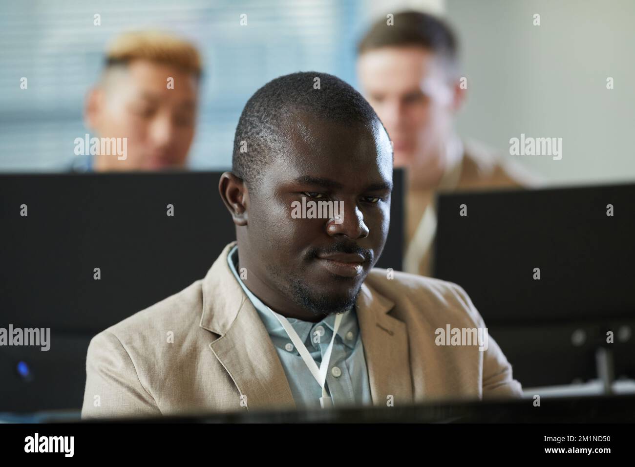 Porträt eines lächelnden schwarzen Mannes, der auf einen Computerbildschirm schaut, während er im Büro des technischen Supports arbeitet Stockfoto