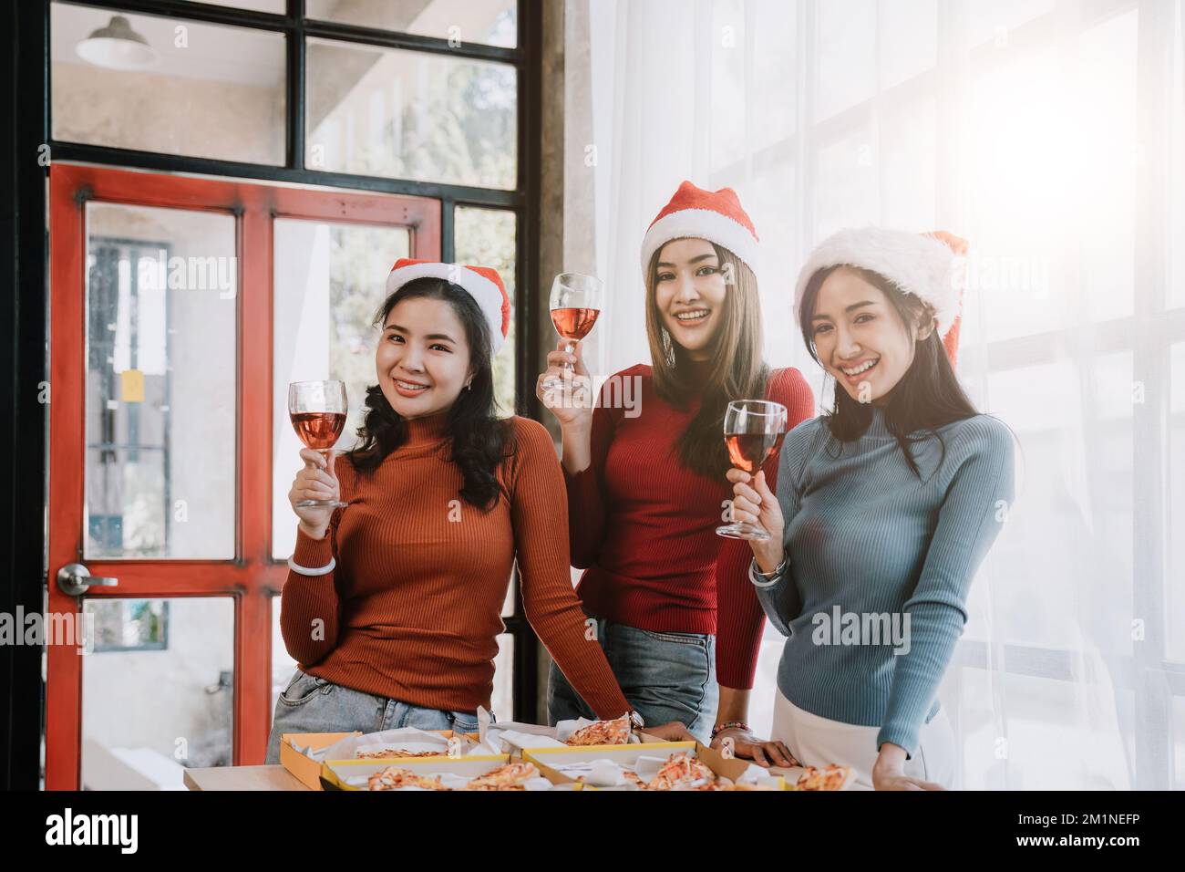 Eine Gruppe asiatischer Freunde versammelt sich, um Weihnachten mit Champagner und Pizza zu Hause zu feiern. Freuden einer Feiertagsparty mit Freunden oder Kollegen Konzept Stockfoto