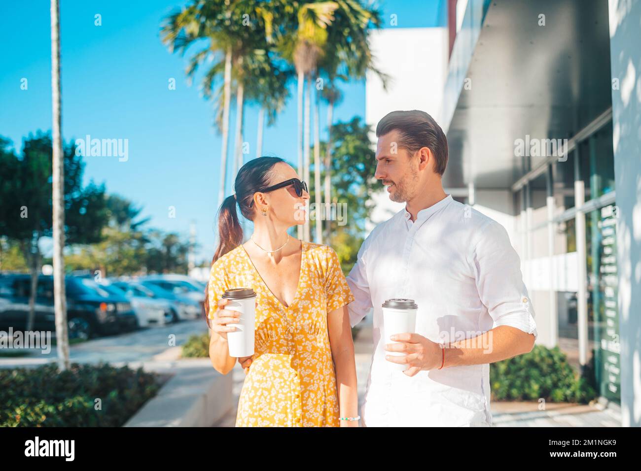 Ein junges Paar mit Kaffee auf der Straße in der Sommerstadt. Junge Erwachsene Touristen auf Reisen in den Sommerferien Stockfoto