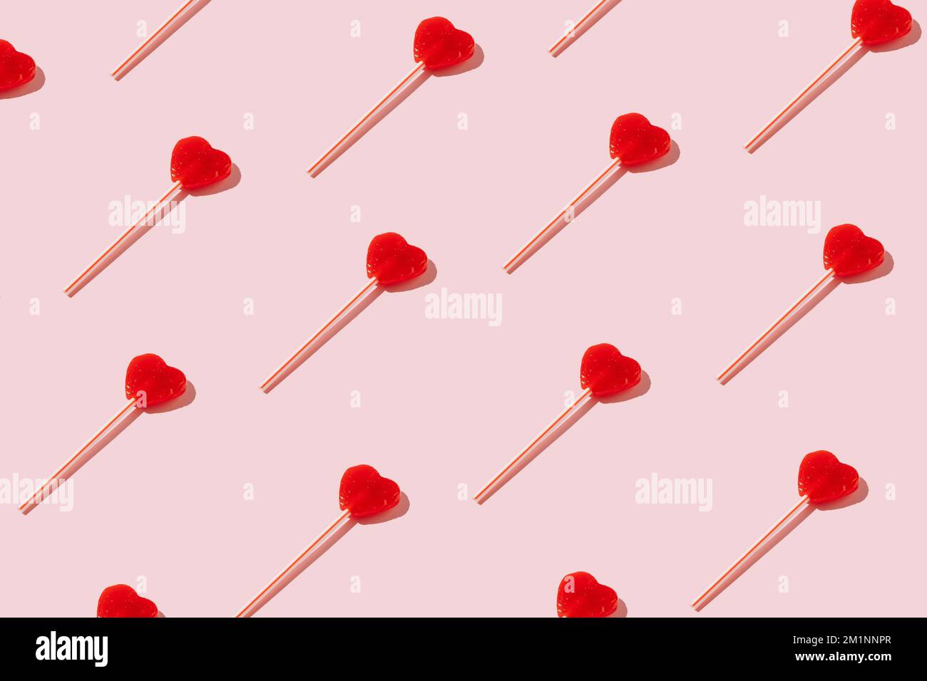 Rotes herzförmiges Lutschmuster auf pastellfarbenem Hintergrund. Minimales Valentinstag-oder-Liebe-Konzept. Stockfoto