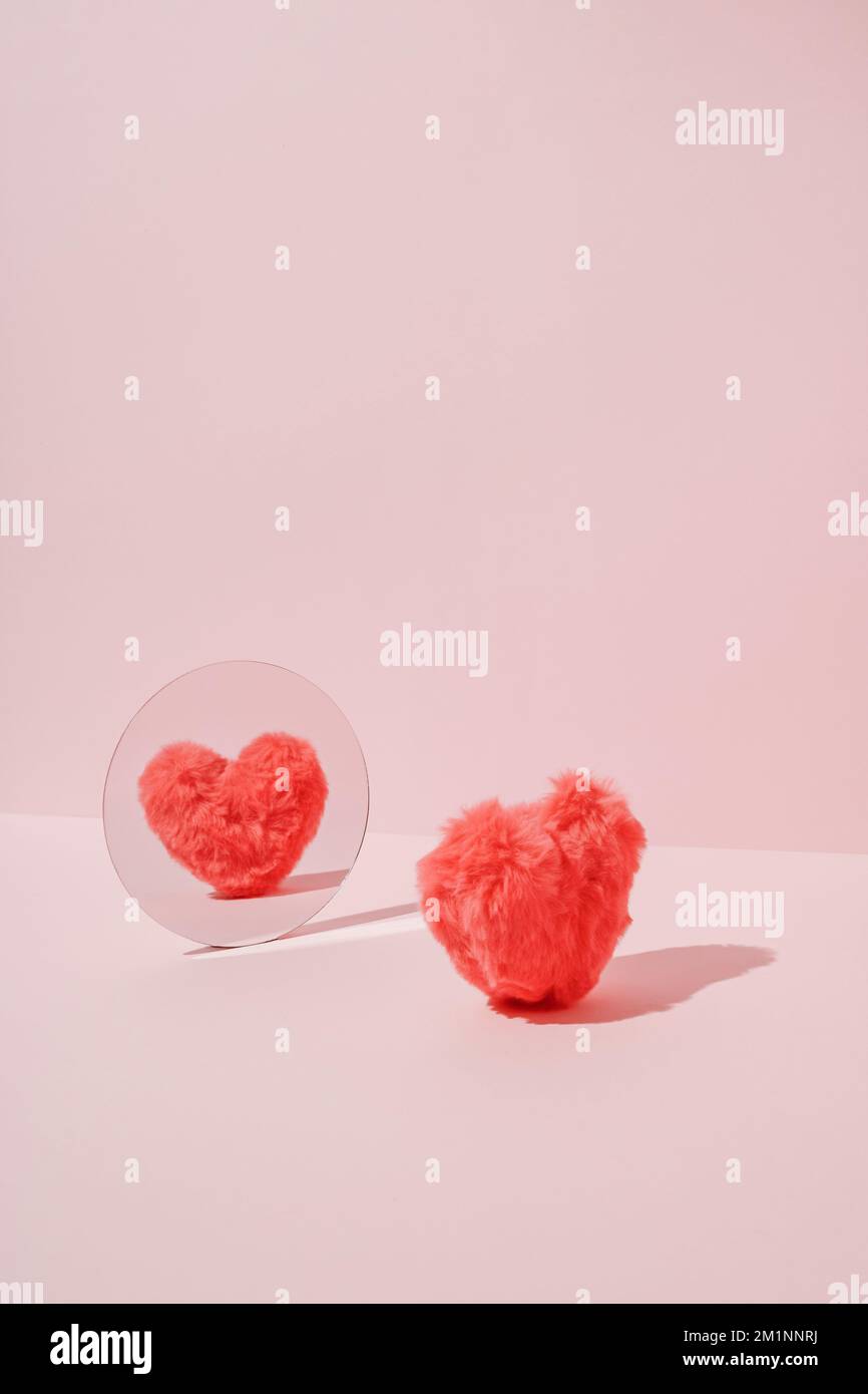 Rosa flauschiges, weiches Herz, das im Spiegel reflektiert. Minimale Liebe oder Valentinskonzept. Stockfoto