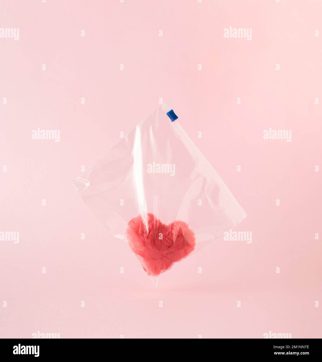 Rosafarbenes flauschiges weiches Herz in Plastiktüte mit Reißverschluss. Minimale Liebe oder Valentinskonzept. Stockfoto