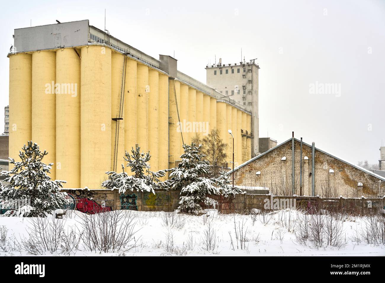 Riga, Lettland - 13. Dezember 2022: Ein altes großes gelbes Getreidelager in der Wintersaison Stockfoto