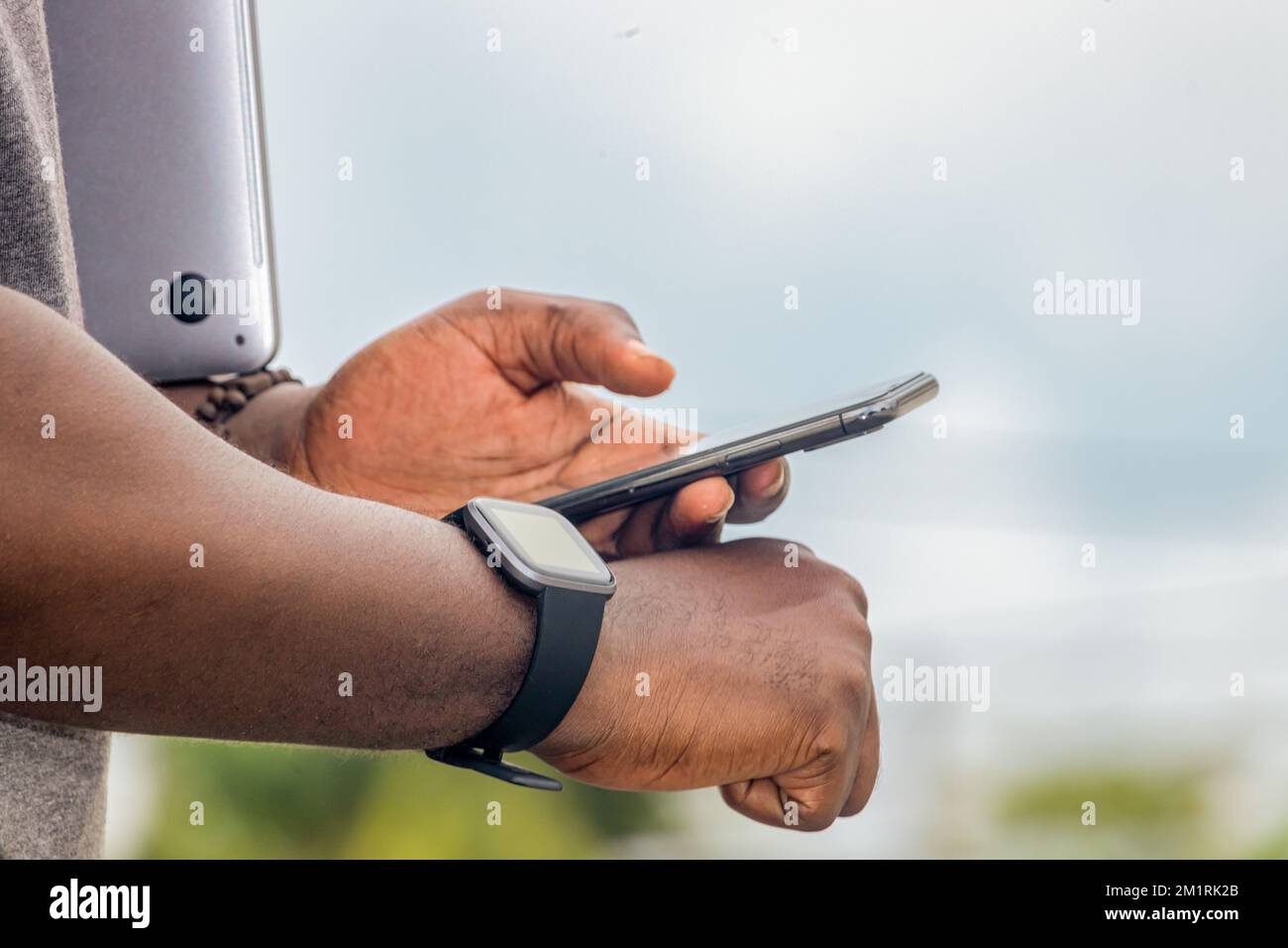 Ein afrikanischer Schwarzer zeigt mit dem Finger auf ein Smartphone in der Stadt, schreibt SMS auf einem Handy, glitzernder Straßenleben, verschwommener Hintergrund Stockfoto