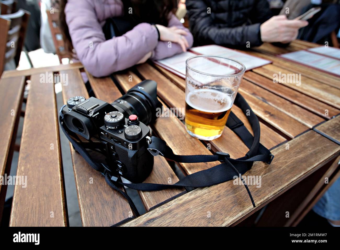 Eine Kamera und ein Glas Bier auf einem Holztisch Stockfoto