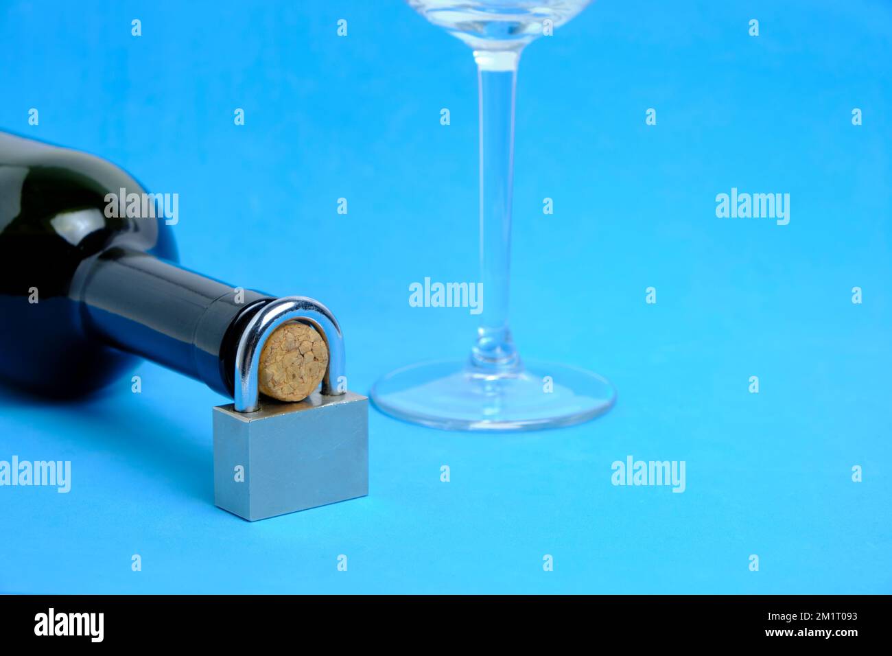Glas und Flasche Wein mit Schlosszunge auf blauem Hintergrund. Konzept Trinkverbot, Verbot Stockfoto