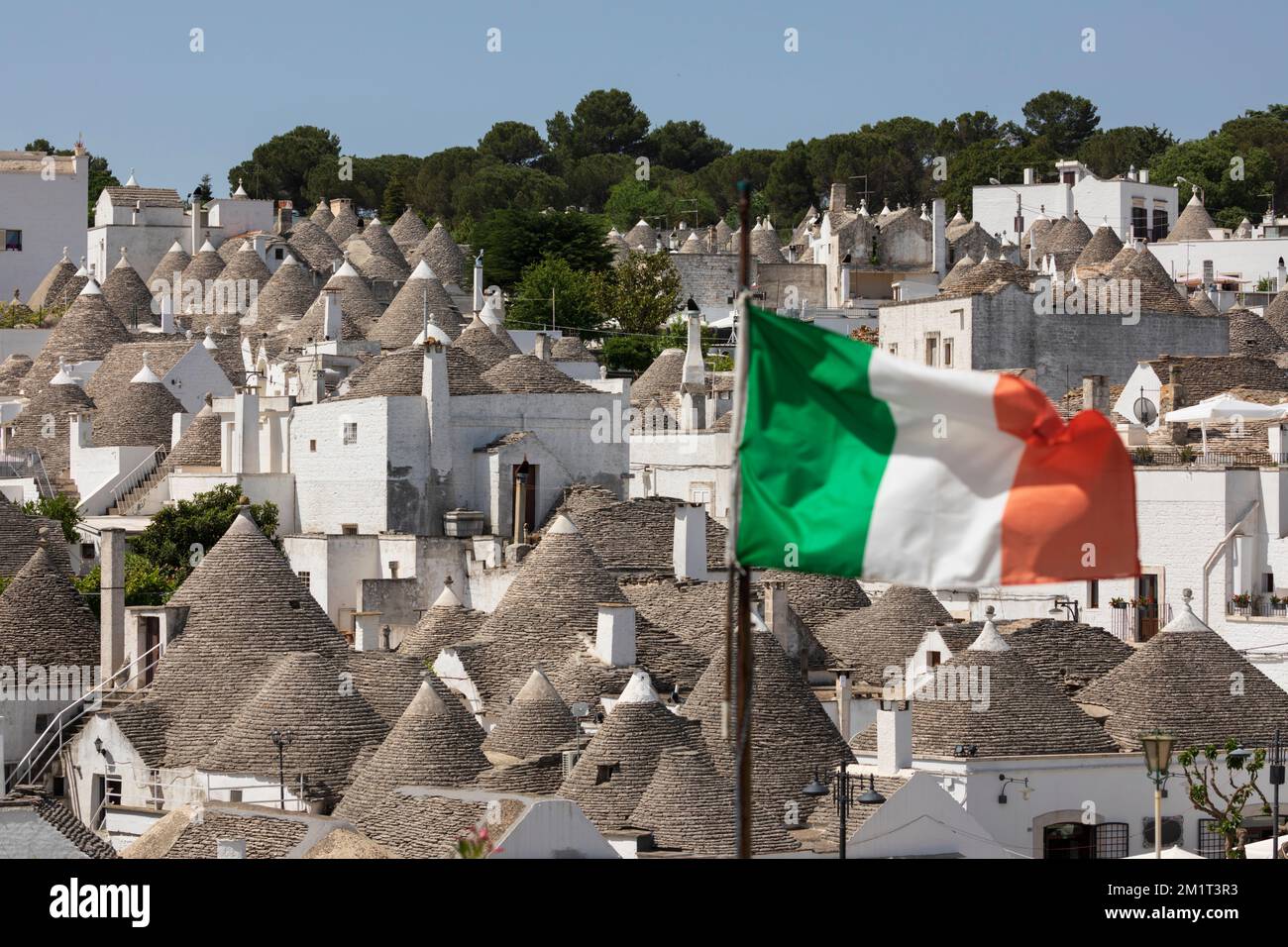 Konische Dächer von Trulli Häusern mit italienischer Flagge in der Altstadt, Alberobello, Apulien, Italien, Europa Stockfoto