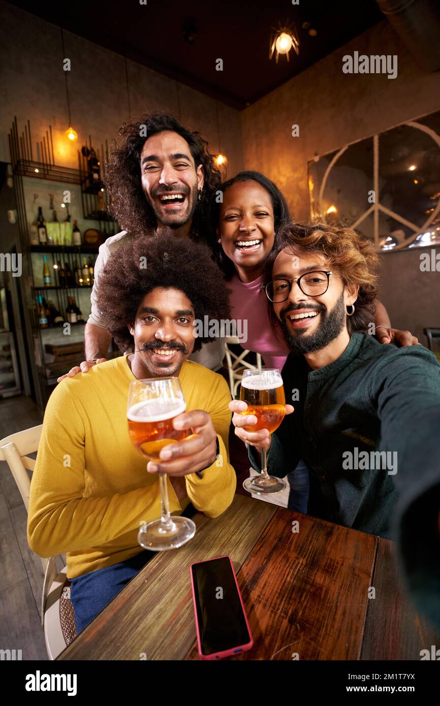 Vertikale Porträtgruppe von Freunden, die in der Restaurant-Bar nach der Arbeit in der Pub-Happy Hour vor die Kamera schauen Stockfoto