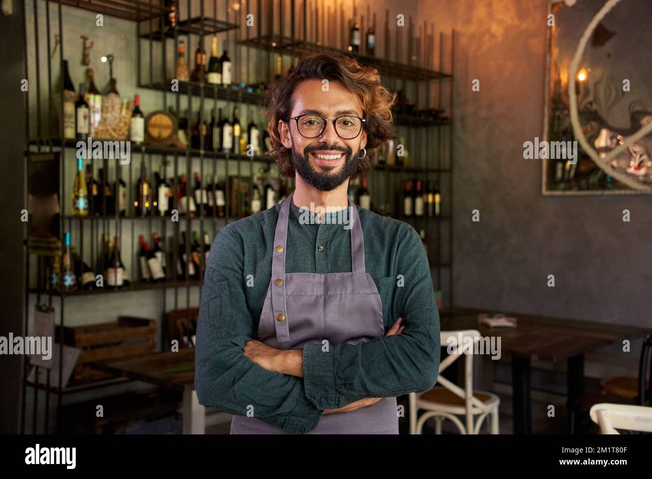 Ich schaue mir das Kameraporträt eines jungen Eigentümers eines kleinen lokalen Unternehmens an. Fröhlicher männlicher Arbeiter, der lächelt Stockfoto