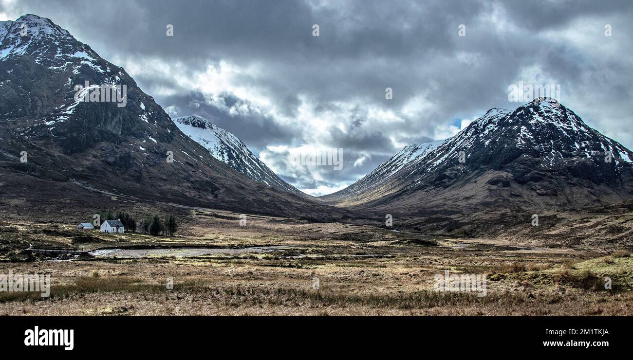 Sturmwolken über dem U-förmigen Tal und üppige Hütte auf Glencoe in den westlichen Highlands. Stockfoto