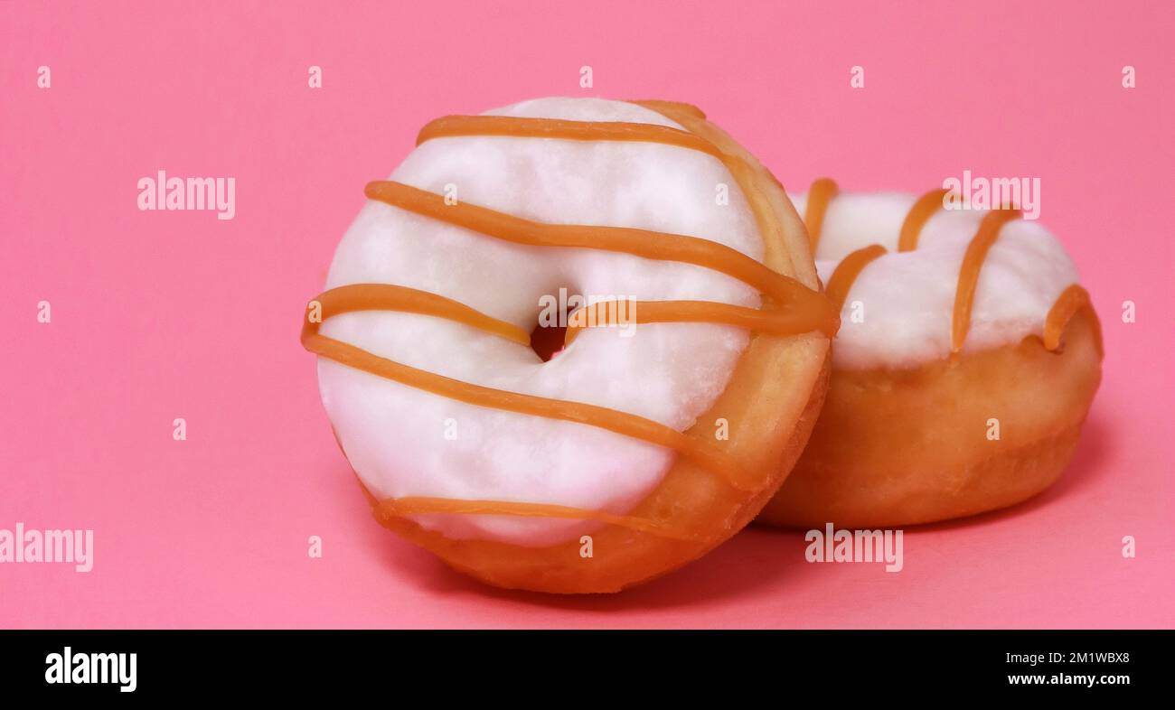 Mini-Donuts mit Zuckerglasur und Karamell auf pinkfarbenem Hintergrund Stockfoto