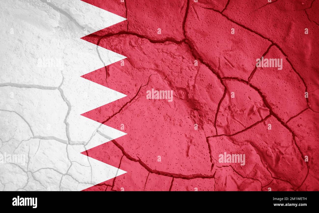 Flagge Bahrains. Bahrain-Symbol. Flagge auf dem Hintergrund von trockener, gerissener Erde. Bahrainische Flagge mit Dürrekonzept Stockfoto