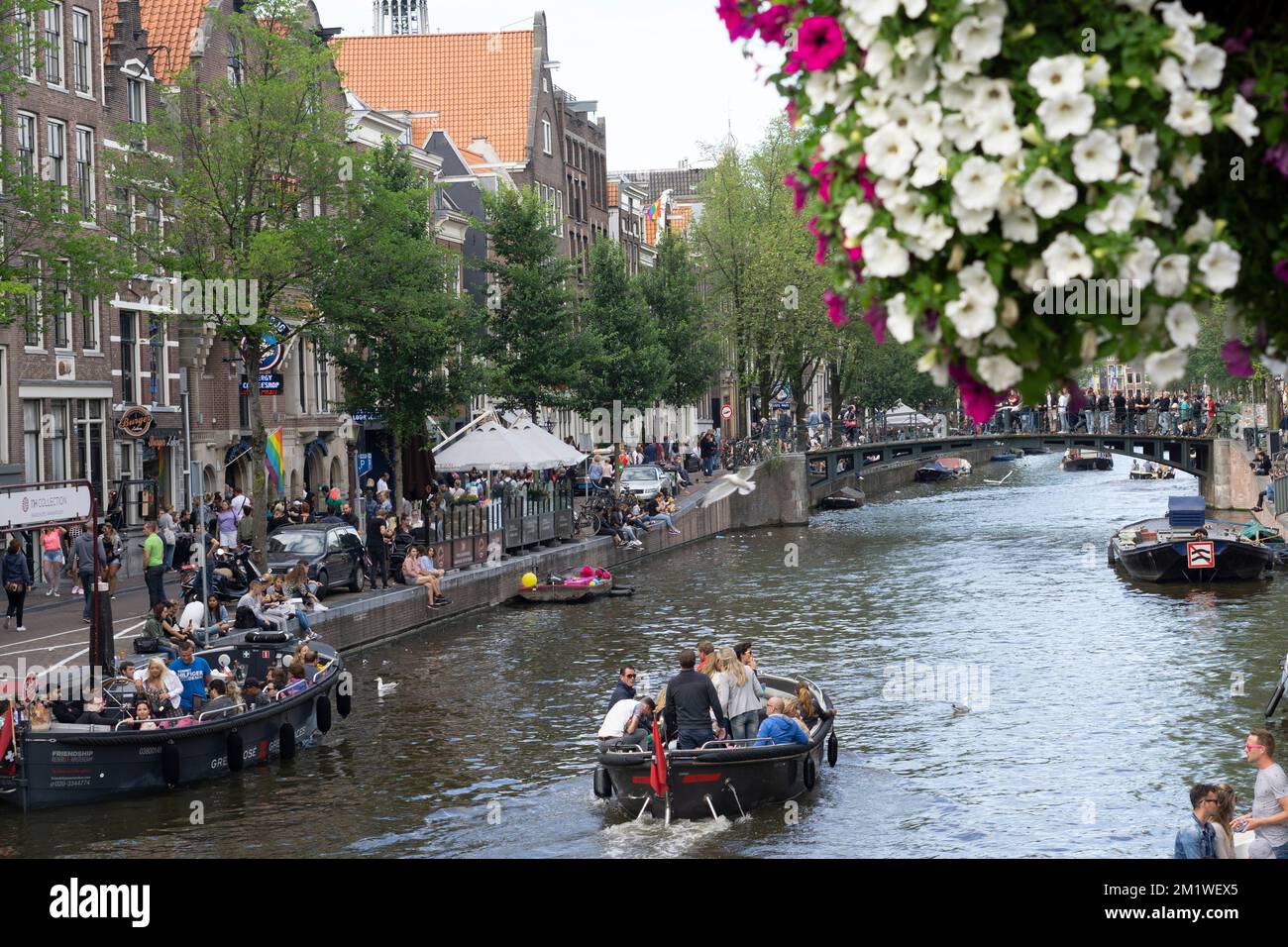 Zwei Boote voller Touristen, die im Sommer in den Amstel-Kanal segeln Stockfoto