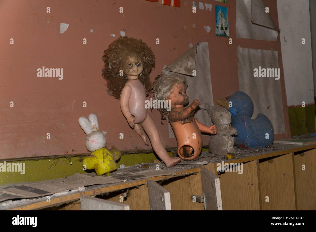 Alte verlassene Puppen und Tierspielzeug über Holzmöbeln in einem kindergarten von tschernobyl Stockfoto