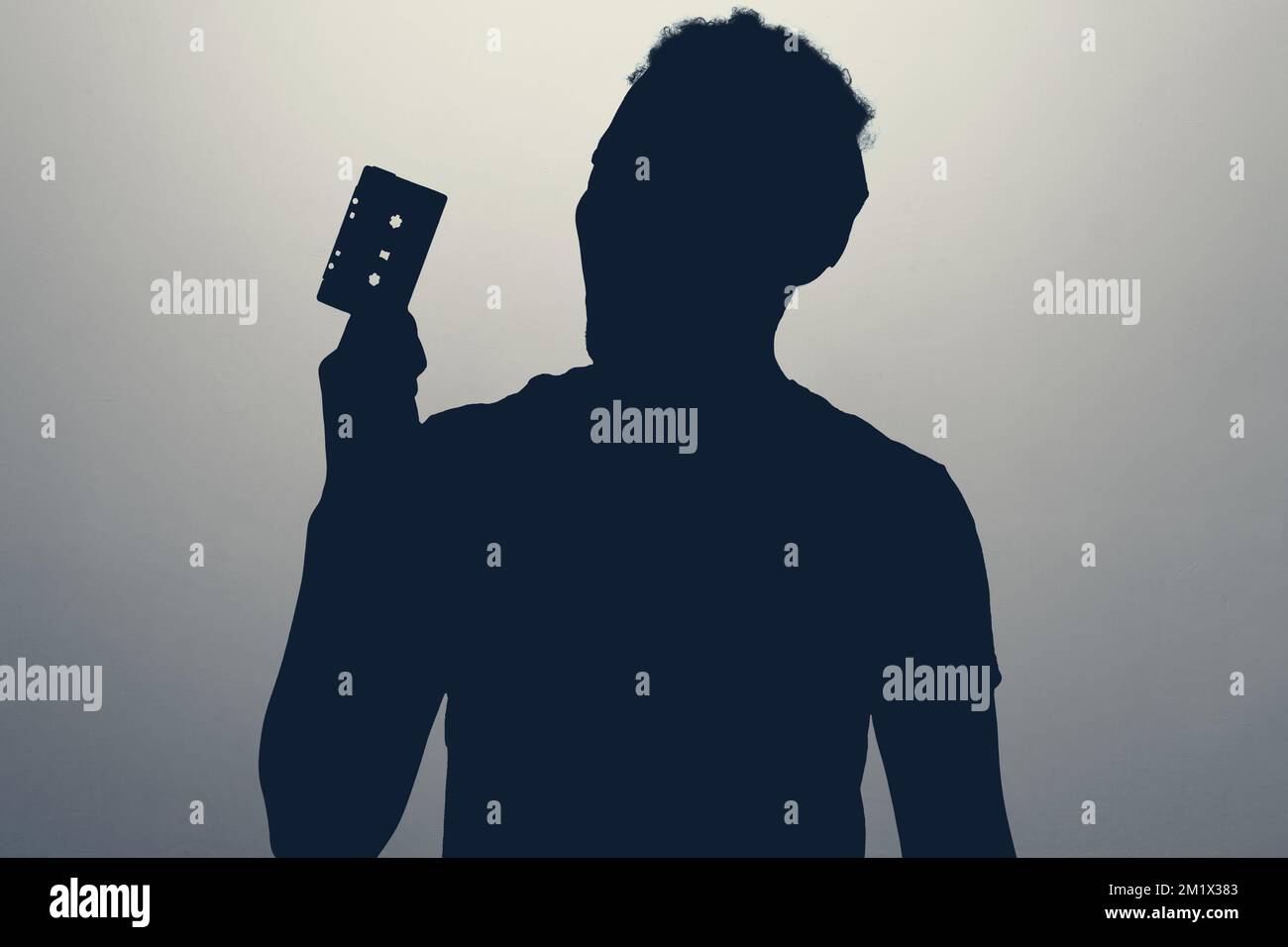 Silhouette eines jungen Mannes mit einem Retro-Kassettenspieler Stockfoto