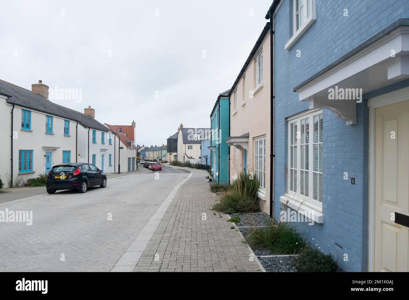 Blaue und cremefarbene Terrassenhäuser auf der Straße Ewyna, einer Straße in Nansledan, eine Entwicklung des Herzogtums Cornwall in Newquay, Cornwall, Südwestengland, Großbritannien Stockfoto