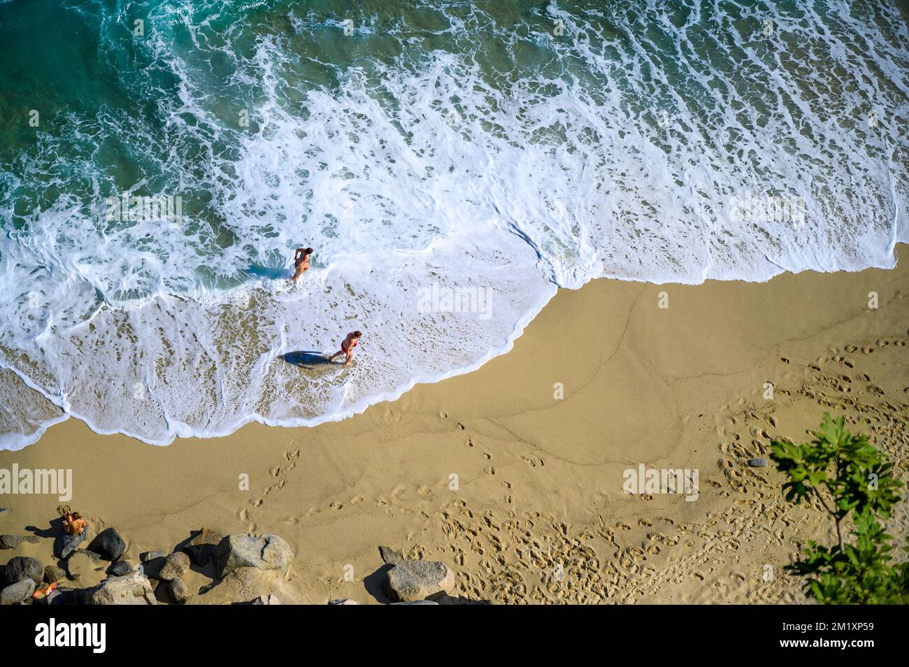 Zwei Frauen wandern in Wellen am Strand von Tropea (Kalabrien, ITALIEN) – aus der Vogelperspektive Stockfoto