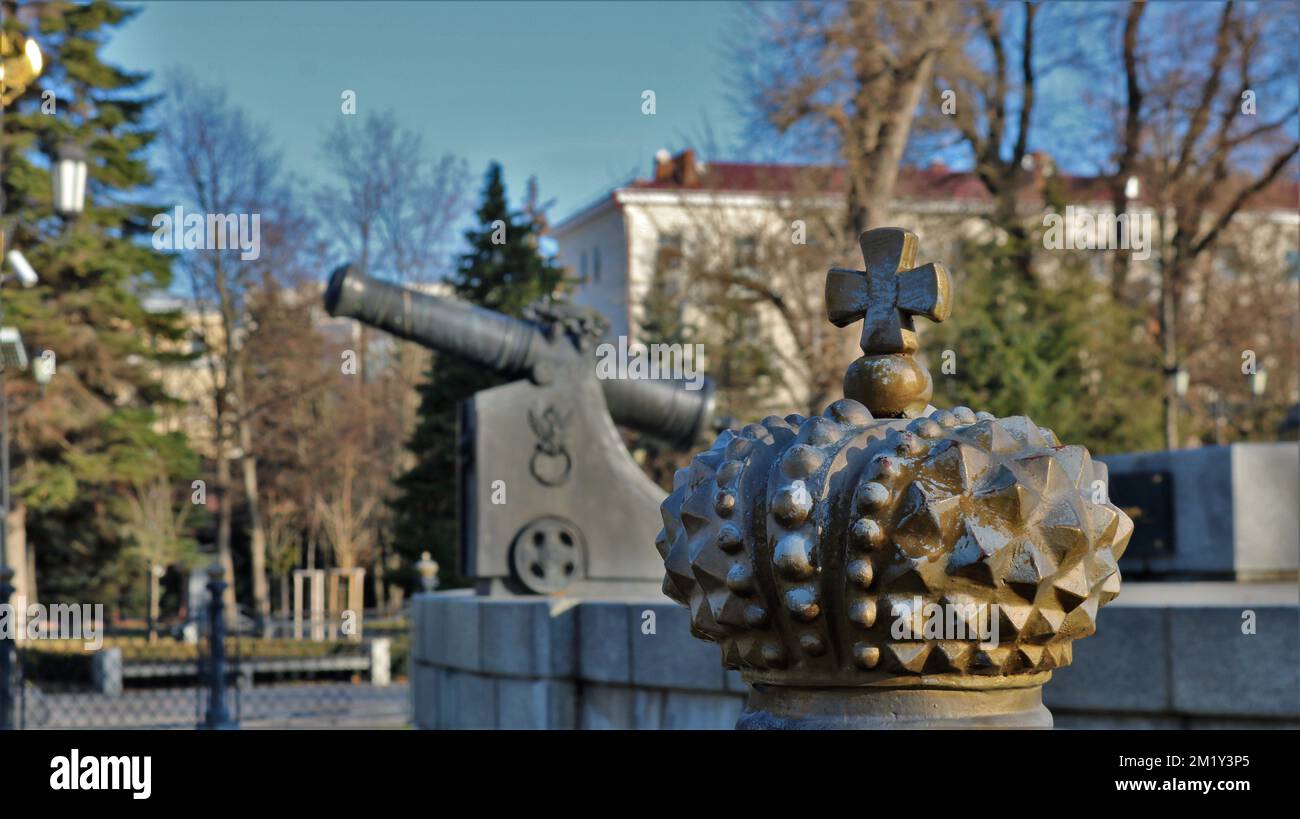 Ein Fragment eines skulpturellen Ensembles eines großen historischen Monuments mit einer kaiserlichen Krone und einer Kanone im Hintergrund Stockfoto