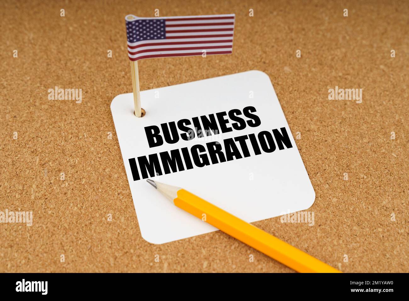 Auf dem Tisch liegen die US-Flagge, ein Bleistift und ein Blatt Papier aus einem Notizbuch mit der Aufschrift "Business Immigration" Stockfoto