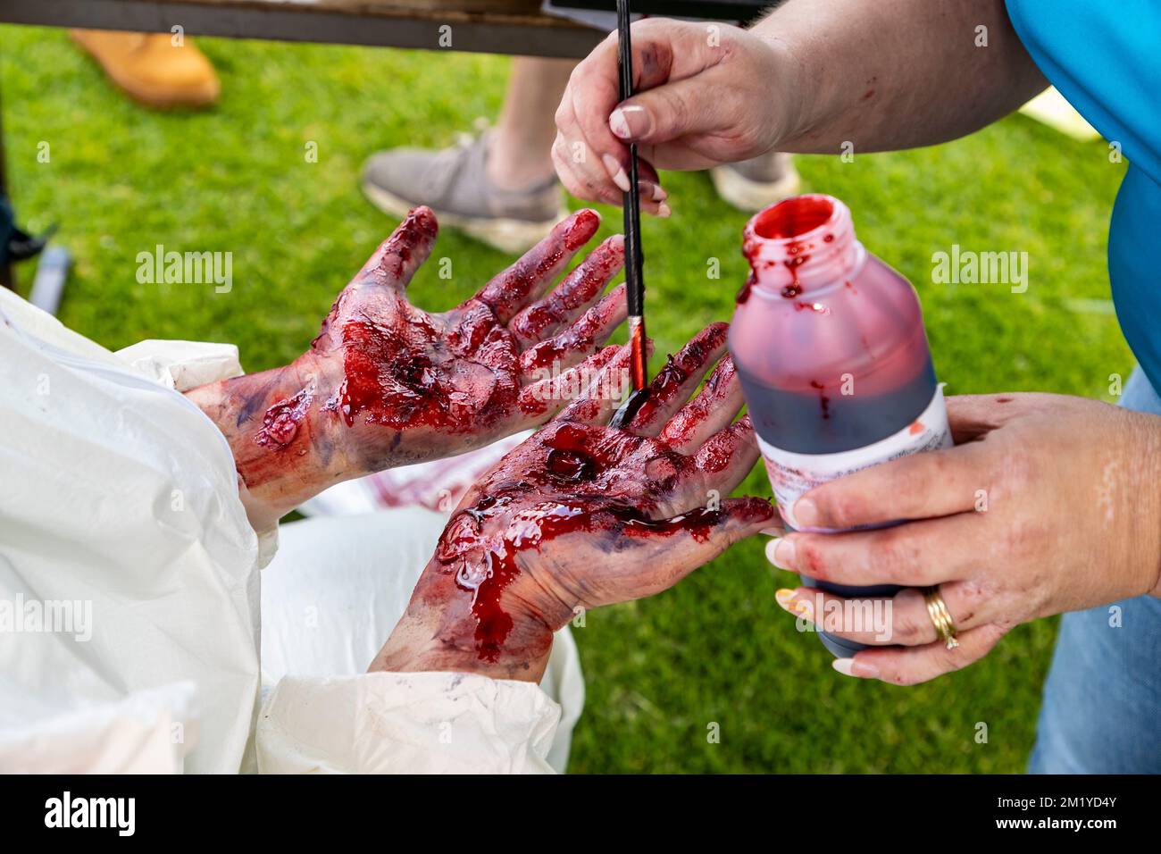 Künstliches Schimmelblut auf einem Handpaar zur Simulation schwerer Verletzungen für eine erste-Hilfe-Trainingsübung Stockfoto