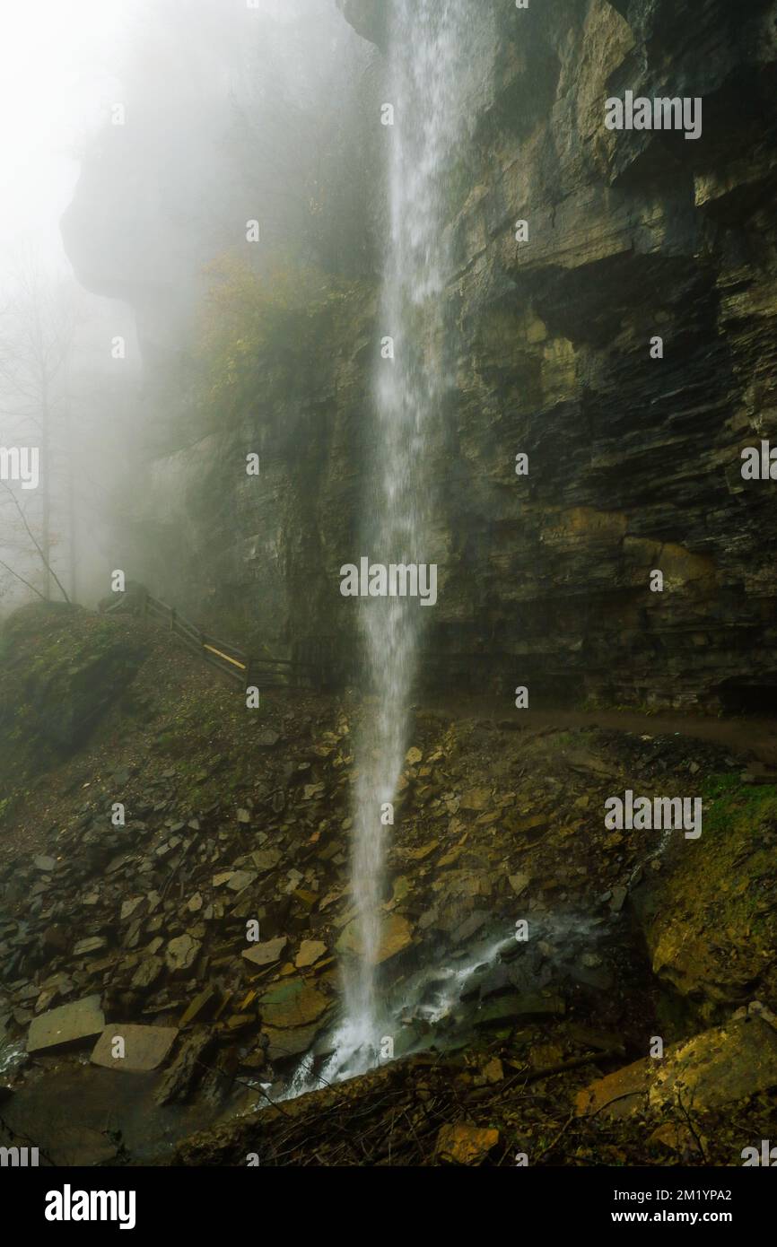 Ein schmaler Wasserfall an einem nebligen Autumtag. Stockfoto