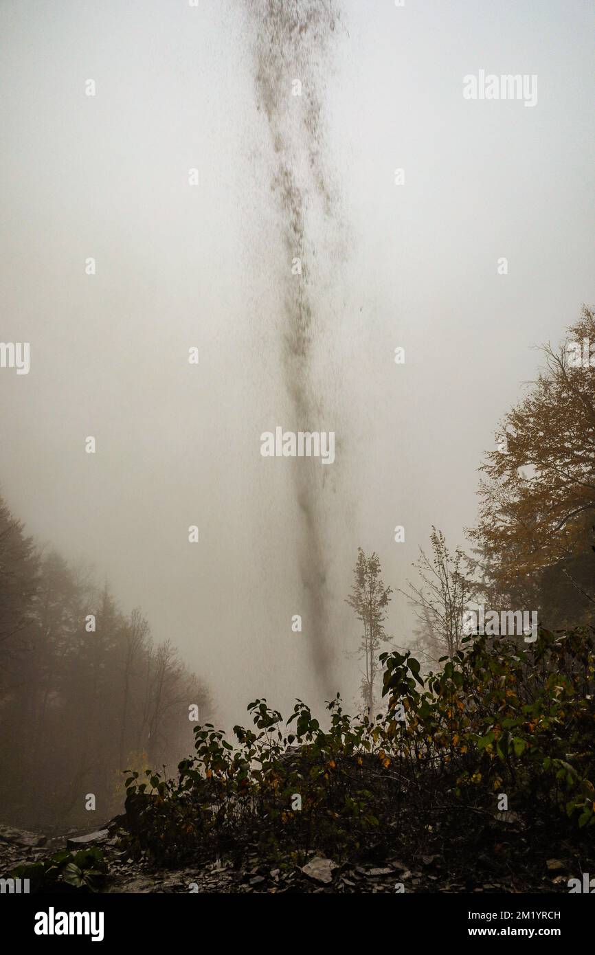 Ein schmaler Wasserfall an einem nebligen Autumtag. Stockfoto