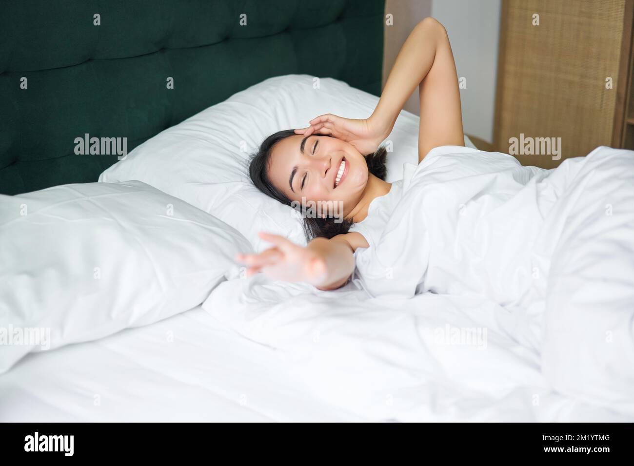 Romantisches asiatisches Mädchen wacht in einem gemütlichen Schlafzimmer  auf, liegt im Bett mit weißen Laken, streckt ihre Hand in Richtung leeres  Kissen Stockfotografie - Alamy