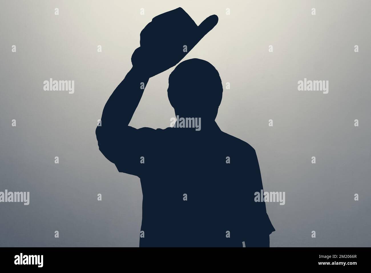 Silhouette eines Mannes, der mit dem Hut wedelt und Hallo oder Willkommen sagt. Anonym-Club-Konzept. Stockfoto