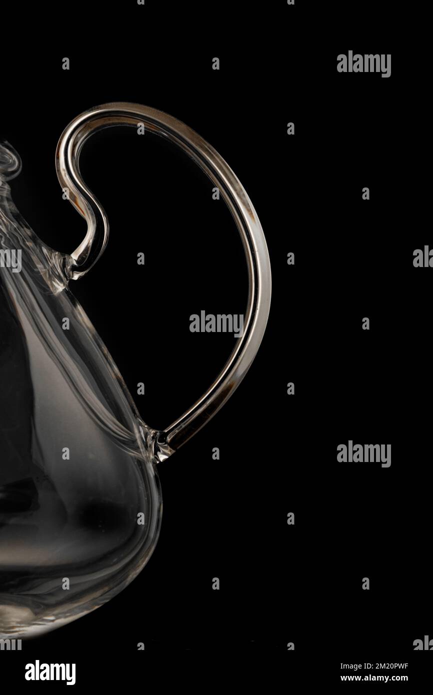 Schöne, transparente Teekanne mit Griff für Nahaufnahmen auf schwarzem Hintergrund Stockfoto