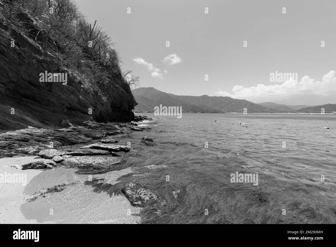 Wunderschöne Schwarz-Weiß-Fotografie der kolumbianischen Tayrona-Landschaft mit felsigem Berg und concha-Bucht im Hintergrund Stockfoto