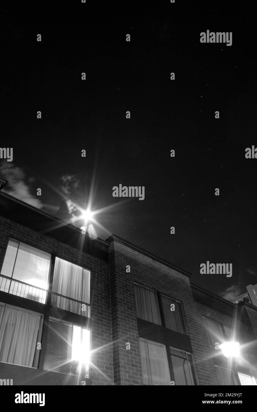 Wunderschöne Schwarz-Weiß-Fotografien der Sternennacht mit Backsteinhaus und Vollmond wie ein großer Stern Stockfoto