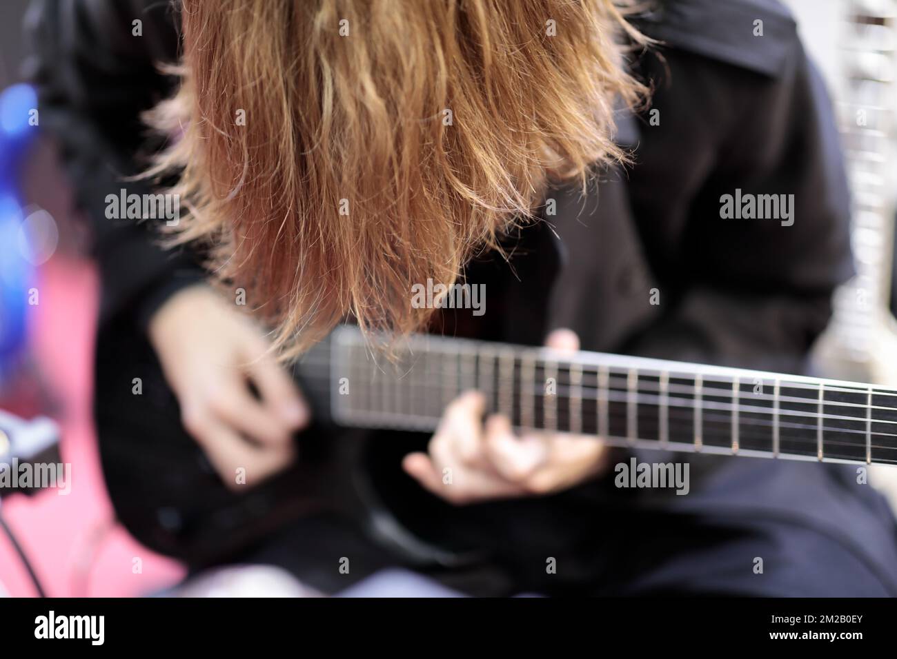 Rockgitarrist mit langen Haaren spielt Elektrogitarre. Selektiver Fokus. Stockfoto
