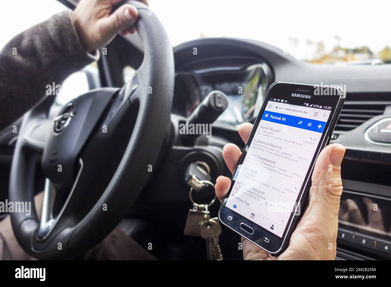 Unverantwortlicher Mann am Lenkrad, der Nachrichten auf Smartphone/Smartphone/Mobiltelefon während der Fahrt mit dem Auto auf der Straße überprüft | Homme derrière volant lisant Nachrichten auf Smartphone/téléphone mobile en roulant en voiture 17/11/2017 Stockfoto