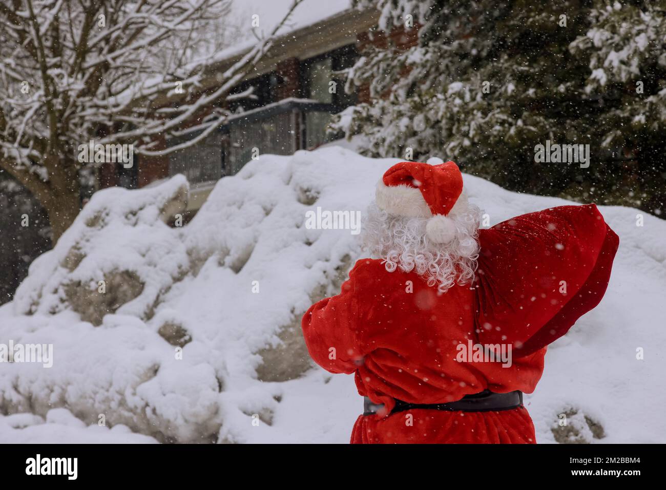 Sehen Sie den Weihnachtsmann mit einer roten Tasche voller Weihnachtsgeschenke, umgeben von weißem Schnee Stockfoto