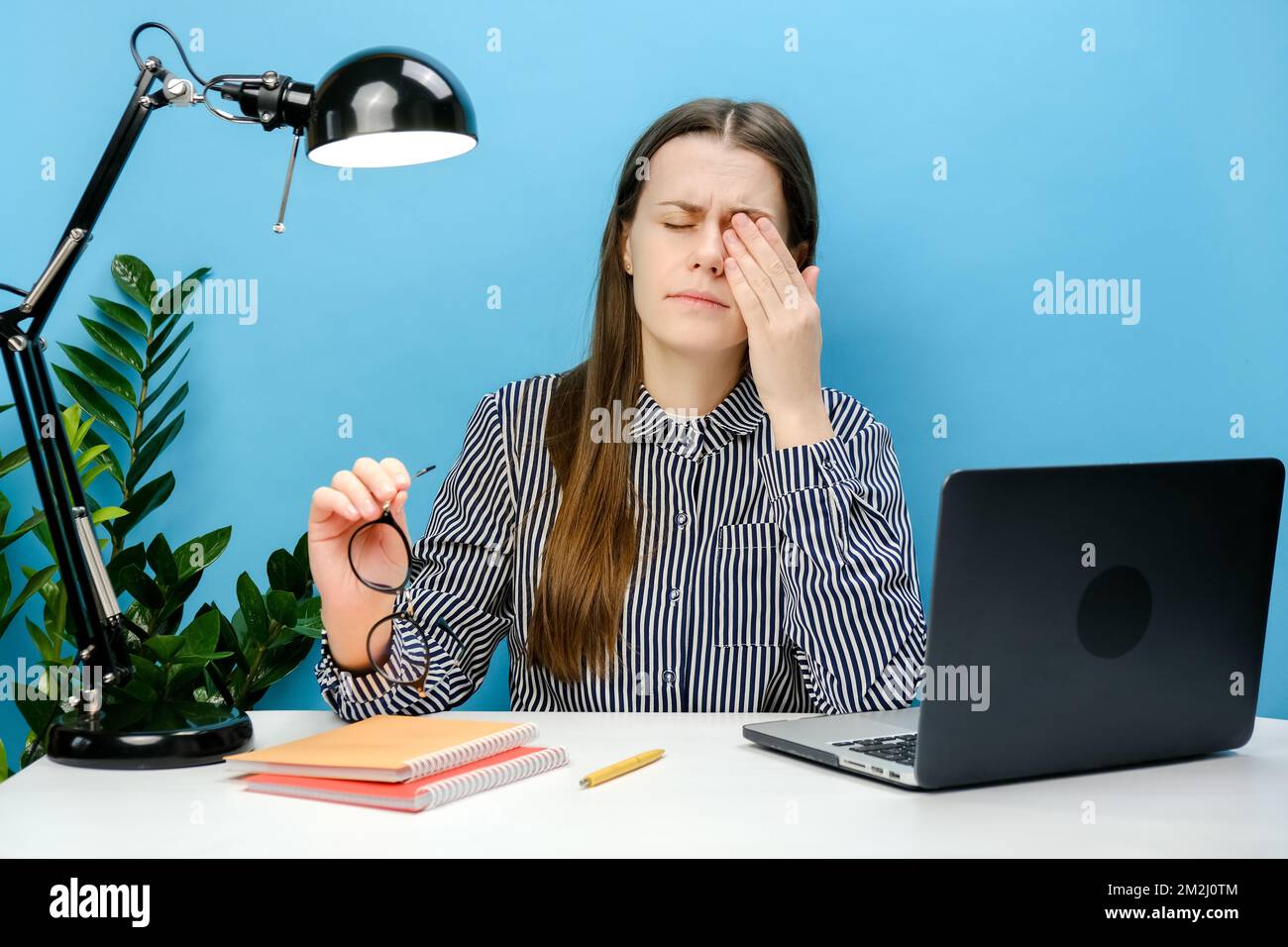 Müde Geschäftsführerin Frau im Alter von 20s Jahren leidet unter Kopfschmerzen schlechte Sicht Probleme beim Arbeiten am Büroschreibtisch mit Laptop, die iso-Position Stockfoto