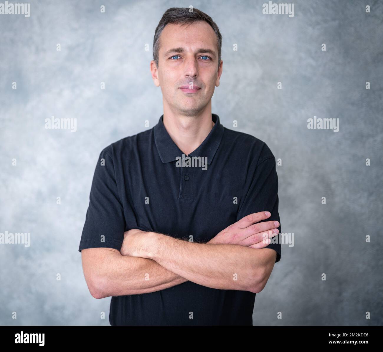 Porträt eines jungen Geschäftsmannes, der vor einem grauen Hintergrund steht. Stockfoto