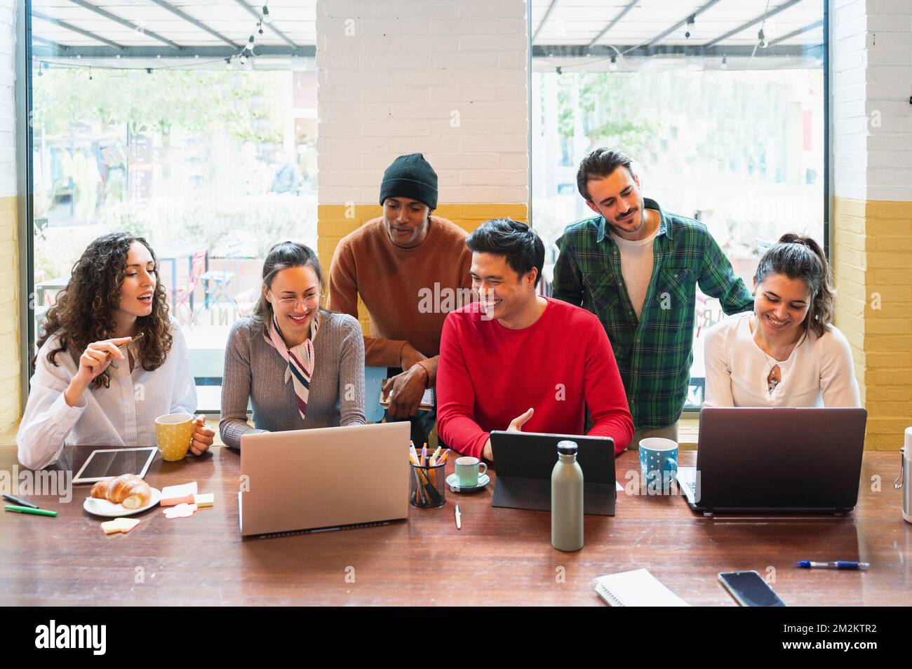 Frontsichtgruppe über junge, multiethnische Menschen mit fröhlichen lächelnden Gesichtern, die in Teamarbeit am Tisch arbeiten. Stockfoto
