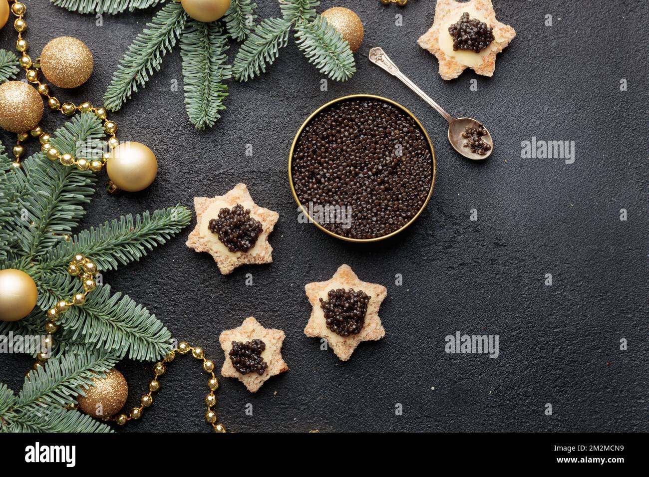 Schwarze Kaviar-Vorspeisen, Sterne auf einem weihnachtlich dekorierten schwarzen Tisch Horizontal Copyspace Stockfoto