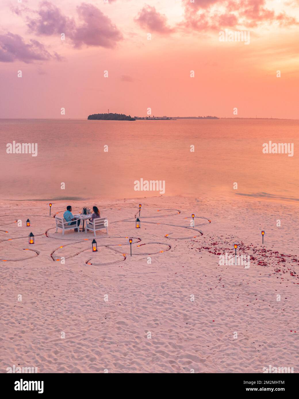 Fantastisches romantisches Abendessen am Strand mit Kerzen und Blumen unter dem Himmel des Sonnenuntergangs. Romantik und Liebe, luxuriöses Restaurant, exotische Tischgestaltung Stockfoto