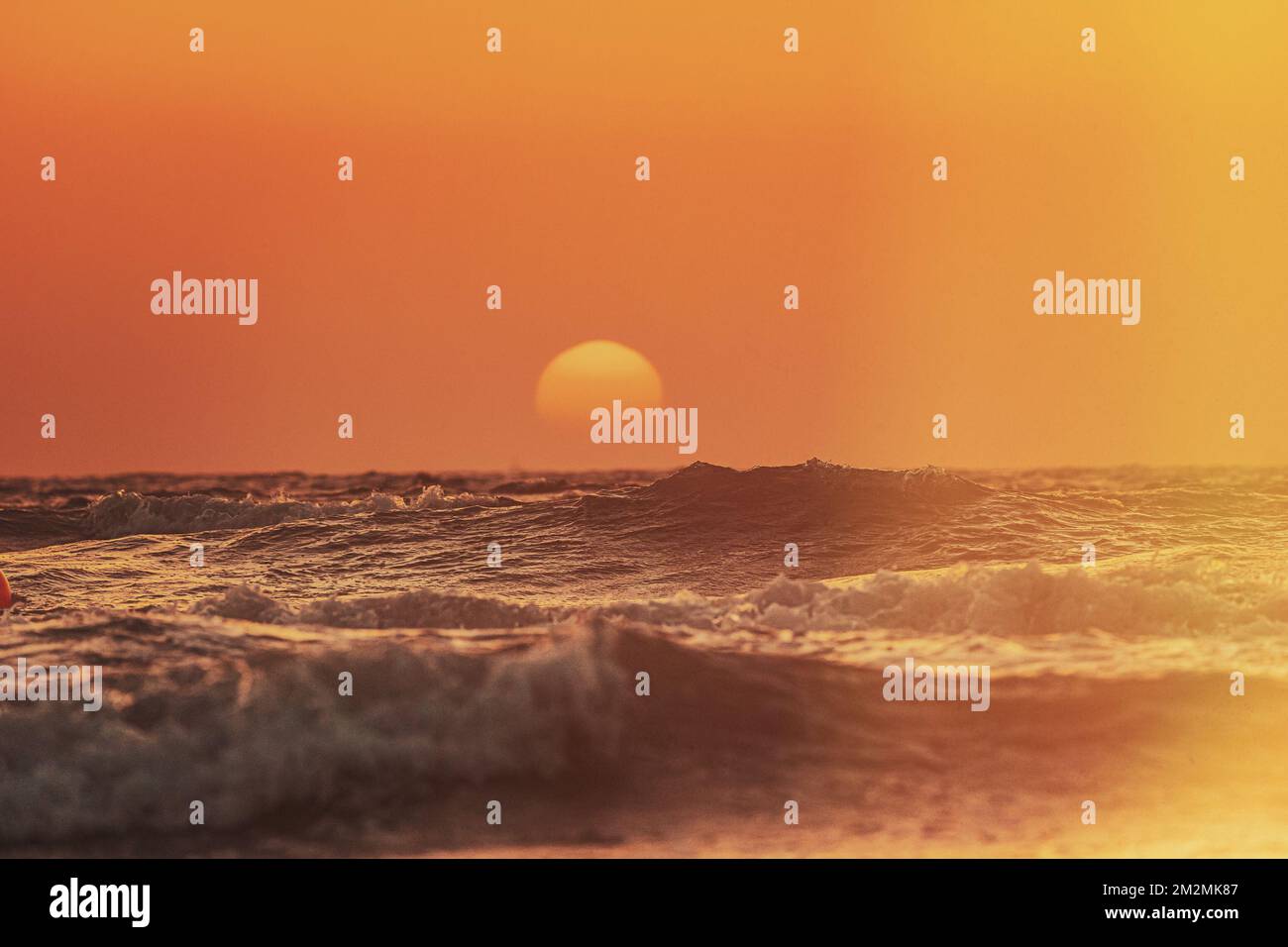 Sonne scheint über dem Horizont bei Sonnenuntergang oder Sonnenaufgang. Abends Meer. Spritzwasser aus Meerwasser. Ozeanwellen in warmen Farben, Sonnenuntergang, Sonnenaufgang, Himmel. Welligkeit Stockfoto
