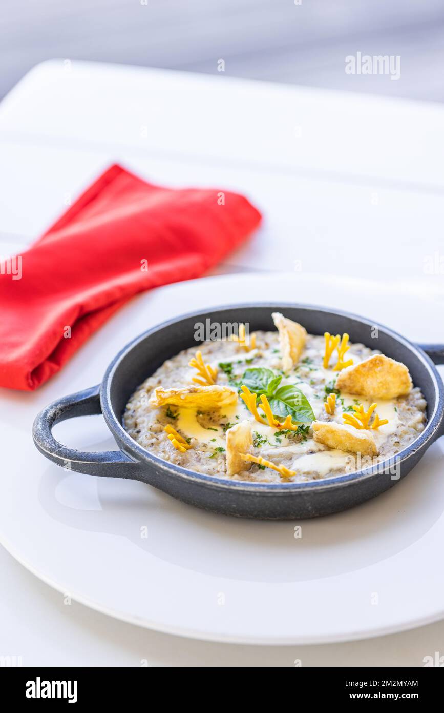 Wunderschönes und leckeres Essen auf einem Teller. Gourmetgericht auf weißem Tisch mit roter Serviette, luxuriöses Hotelresort-Spezialgericht. Trüffelpilze und Gemüse Stockfoto