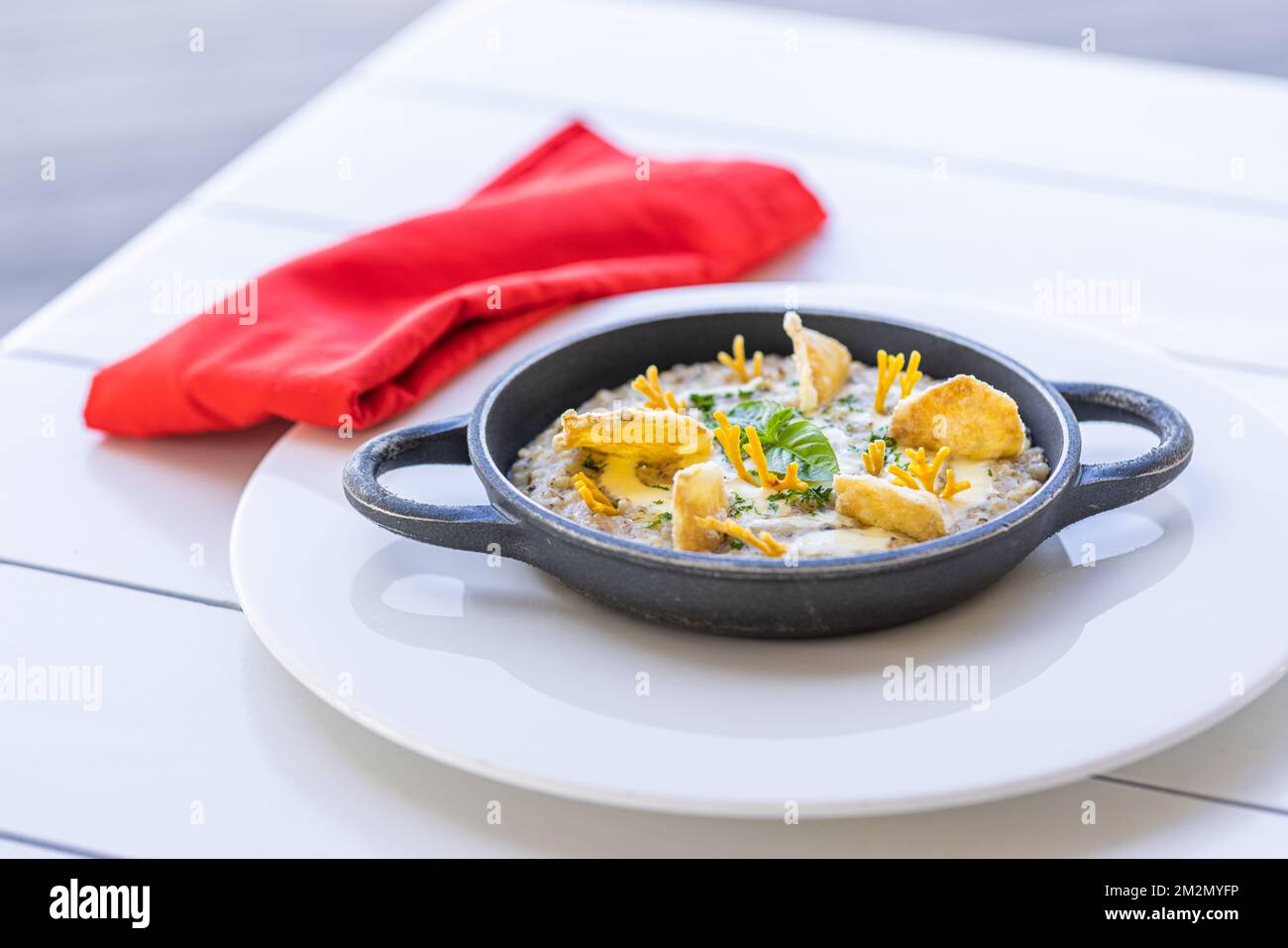 Wunderschönes und leckeres Essen auf einem Teller. Gourmetgericht auf weißem Tisch mit roter Serviette, luxuriöses Hotelresort-Spezialgericht. Trüffelpilze und Gemüse Stockfoto