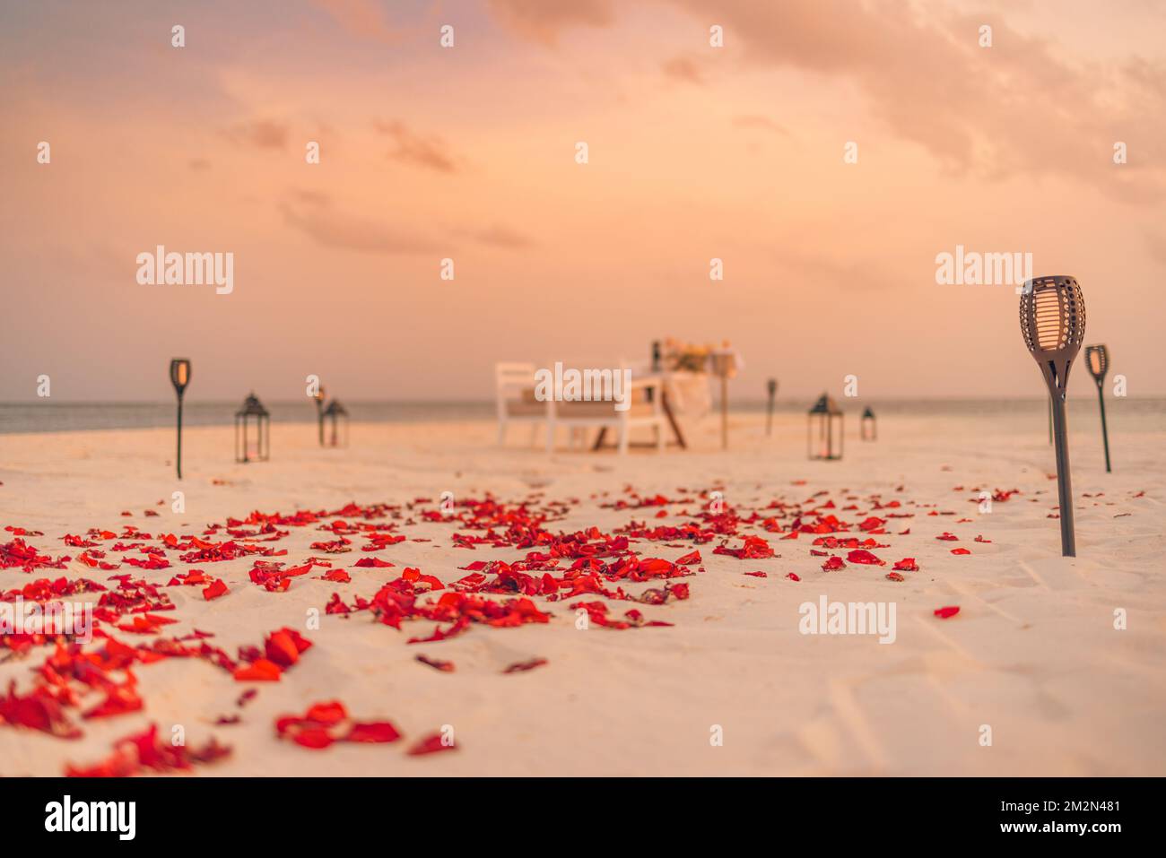 Fantastisches romantisches Abendessen am Strand mit Kerzen und Blumen unter dem Himmel des Sonnenuntergangs. Romantik und Liebe, luxuriöses Restaurant, exotische Tischaufteilung Stockfoto