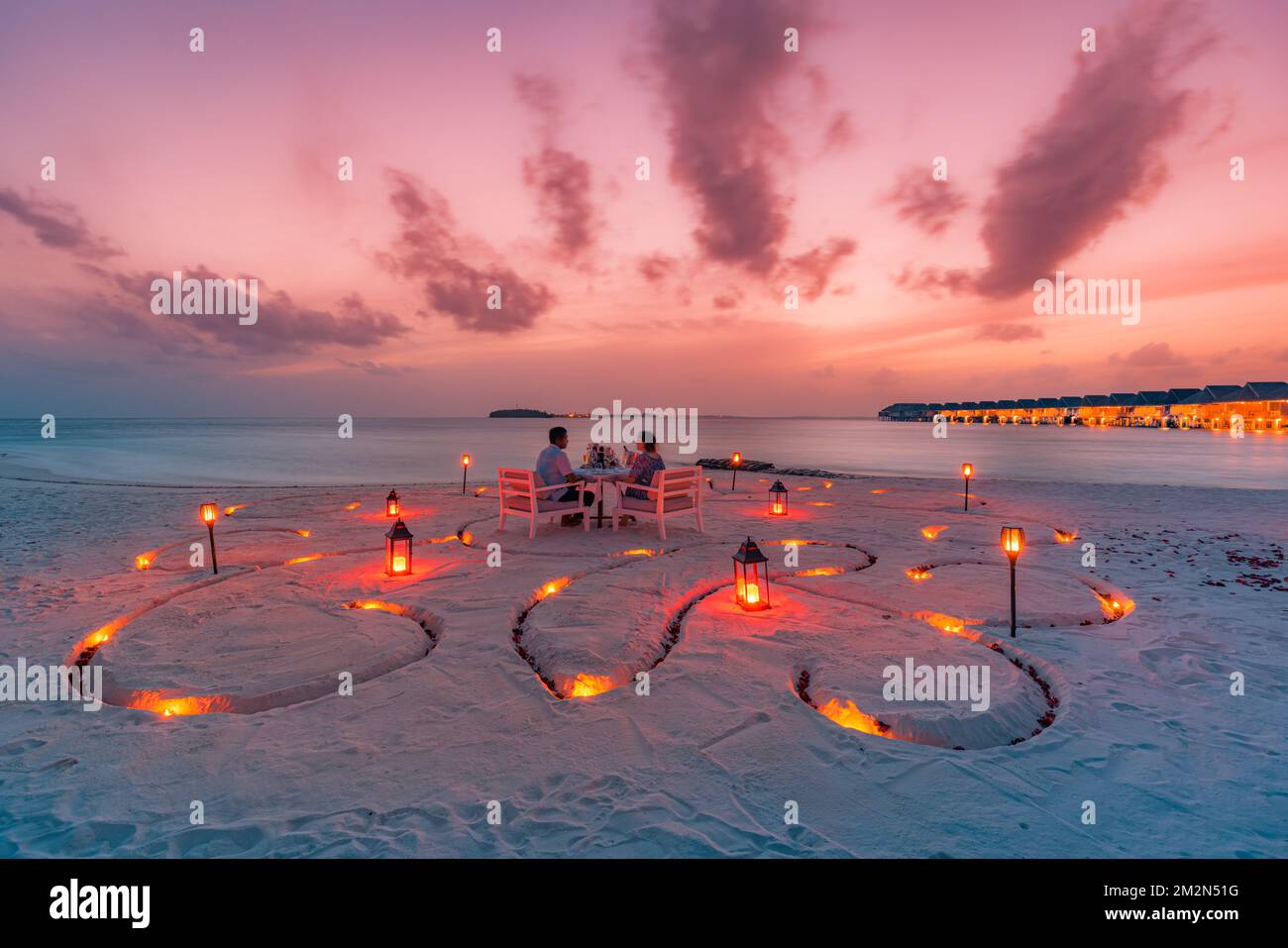 Fantastisches romantisches Abendessen am Strand mit Kerzen und Blumen unter dem Himmel des Sonnenuntergangs. Romantik und Liebe, luxuriöses Restaurant, exotische Tischgestaltung Stockfoto