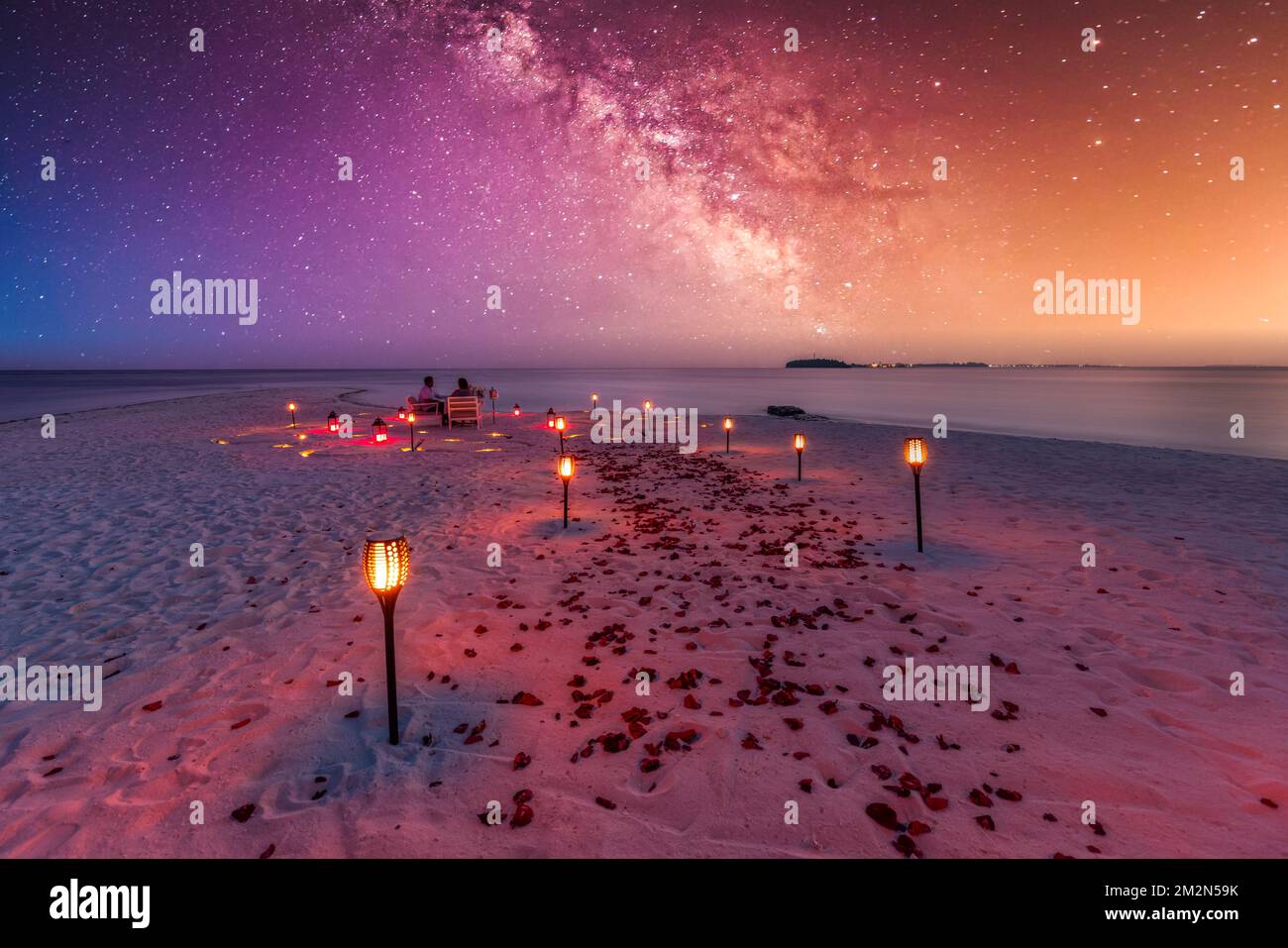 Fantastisches romantisches Abendessen am Strand mit Kerzen und Blumen unter dem Himmel des Sonnenuntergangs. Romantik und Liebe, luxuriöses Restaurant, exotische Tischgestaltung Stockfoto