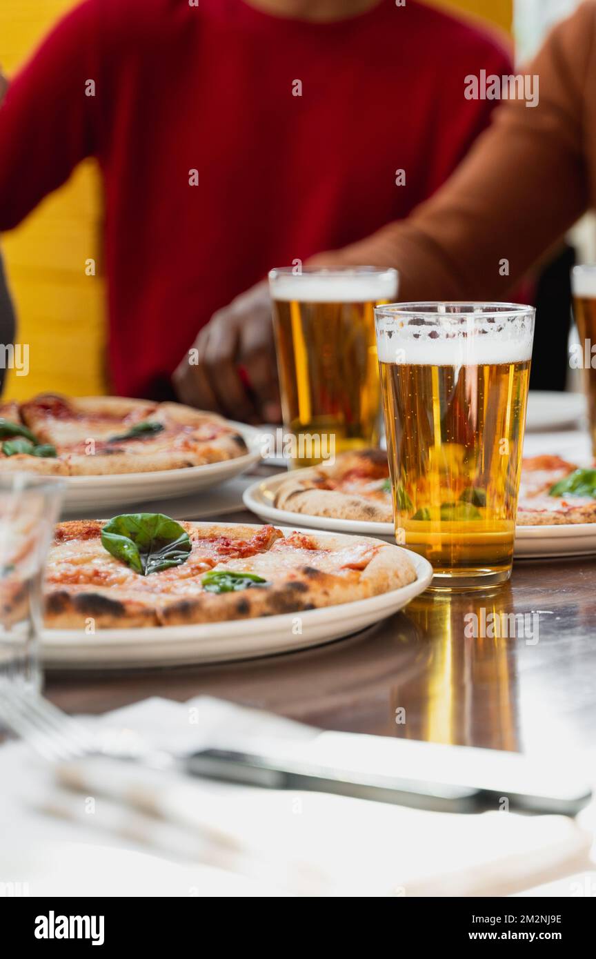 Vertikale italienische Pizza margherita auf dem Tisch mit Gläsern Bier ...
