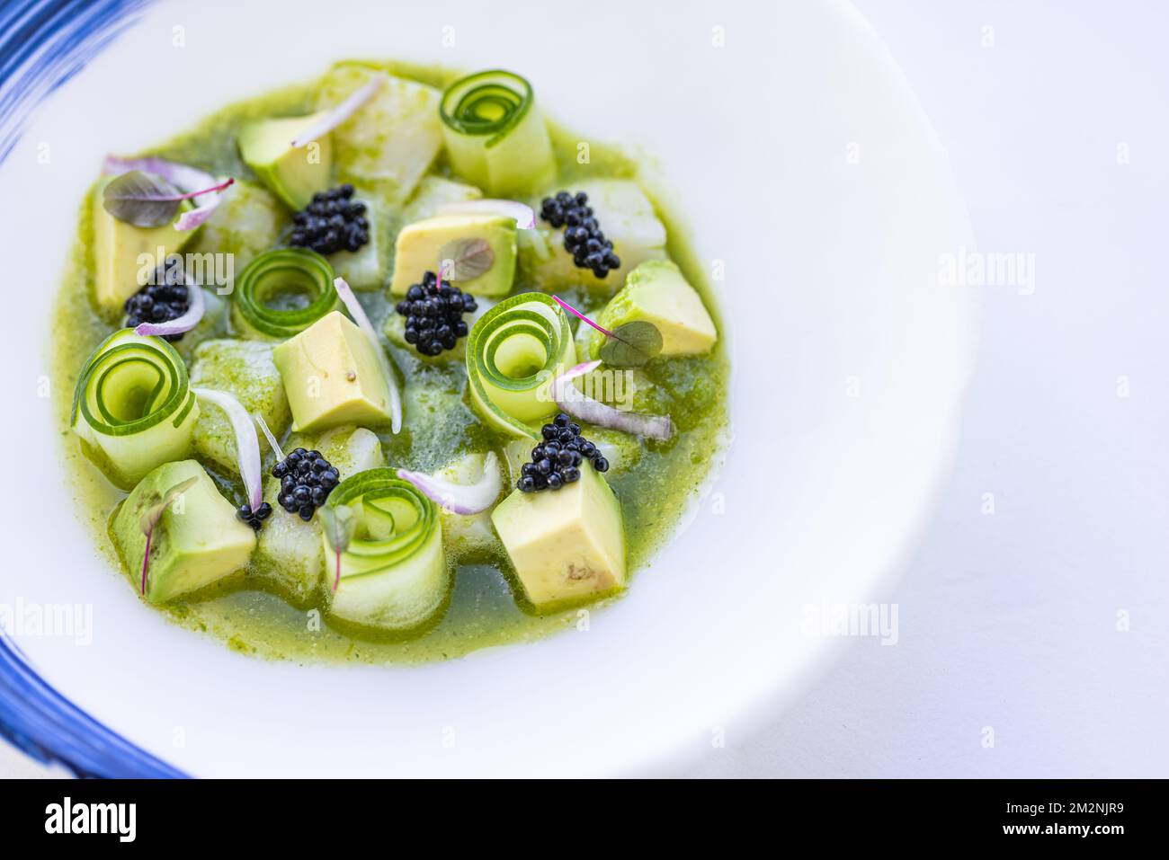 Gourmet-Luxus-Salat mit Blick von oben. Gurke mit Himbeere und Avocado. Blick auf Makroküche auf weißem Teller, köstliche Vorspeise oder vegane Salatvorlage Stockfoto